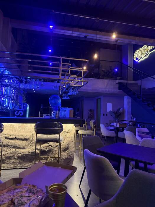 La barra de Alquimia Resto Bar de noche, con luces azules.